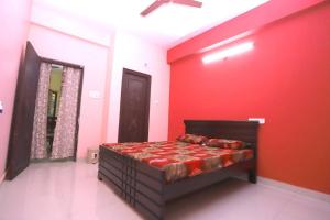 Un dormitorio con una pared roja y una cama en Lalitha Residency, en Secunderābād