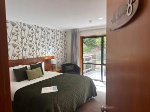 ワナカにあるWanaka Springs Lodgeのベッドとバルコニー付きのホテルルーム