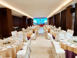 Phoenix Hill Hotel Dongguan - Golf Course Shop في دونغقوان: قاعة احتفالات بطاولات بيضاء وكراسي بيضاء