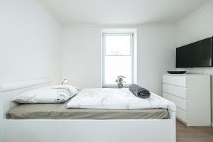 1 dormitorio blanco con 1 cama y TV de pantalla plana en fewo1846 - FlensBo II - komfortable Wohnung mit 2 Schlafzimmern und Terrasse, en Flensburg
