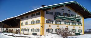 a large yellow and white building in the snow at Taffenreutherhof in Achenmühle