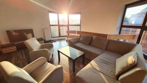 een woonkamer met een bank en stoelen en een tv bij Zen Harmony Hideaway - private luxury rooms with AC in long-term shared apartment in Boedapest