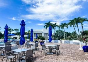 a patio with tables and chairs with blue umbrellas at Naples Luxury Condo, Pool, Tennis, Minutes from the Beach in Naples
