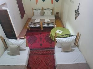 a room with two beds and a table at Riad Assia Foum Zguid in Foum Zguid