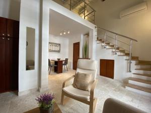 a living room with a white chair and stairs at The Sanctuary in Santo Domingo