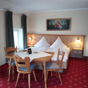 a hotel room with a bed and a table and chairs at Beim Haasen in Grabenstätt