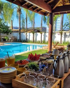 a table with plates of food next to a pool at Pousada Caraíba in Rifaina