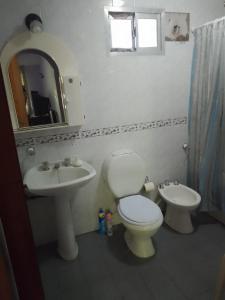 uma casa de banho com um WC, um lavatório e um espelho. em EL TERO em Sierra de los Padres