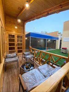 une terrasse couverte en bois avec un canapé et des chaises sur la terrasse. dans l'établissement شاليه أرياف Chalet Aryaf Yanbu, à Yanbu