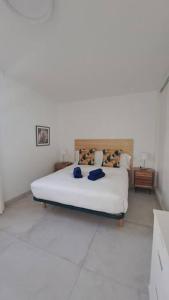 a bedroom with a white bed with two blue pillows at Babor Sunset Playa Honda in Playa Honda