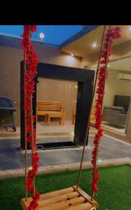 a wooden swing with red flowers in a yard at شاليهات درة بارك الشقيق in Ash Shuqayq