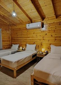 two beds in a room with wooden walls at شاليه أرياف Chalet Aryaf Yanbu in Yanbu