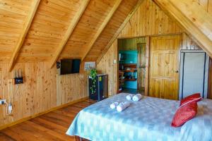 1 dormitorio con 1 cama en una habitación de madera en Cabaña Indira, en Monteverde
