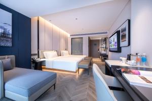 広州市にあるAtour Hotel Guangzhou Panyu Jewelry Cityのベッド、テーブル、椅子が備わるホテルルームです。