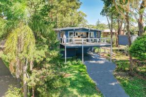 an aerial view of a blue house in the trees at Bannister Head Beach House in Narrawallee