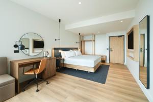 a bedroom with a bed and a desk and a mirror at Hilton Garden Inn Busselton in Busselton