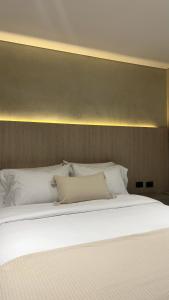 Elle comprend un grand lit avec des draps et des oreillers blancs. dans l'établissement Sonata 44 Hotel Laureles, à Medellín