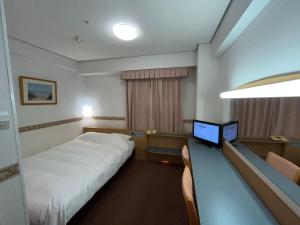 a hotel room with a bed and a desk with a laptop at Hotel Alpha-One Niihama in Niihama