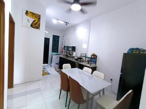 a dining room with a white table and chairs at Manjung Point Homestay in Seri Manjung