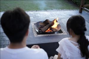 a couple of people standing around a fire pit at Seaside Villa KAMANO in Aji