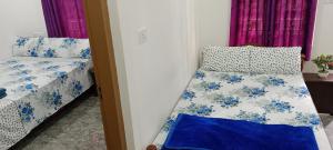 Silver home stay vagamon في فاغامون: غرفة نوم بسريرين ذات شراشف زرقاء وبيضاء