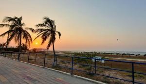 a beach with two palm trees and the sunset at Luna Nueva Casa de Huéspedes in Ríohacha