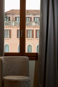 una silla y una ventana con vistas a un edificio en Palazzina RIVA, en Venecia
