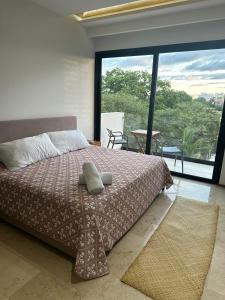 a bedroom with a bed and a large window at Smart Home Luxury Condo 5ta avenida in Playa del Carmen