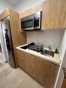 a kitchen with a sink and a microwave and a refrigerator at Smart Home Luxury Condo 5ta avenida in Playa del Carmen