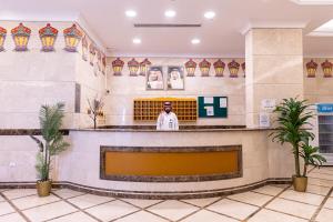 a man standing at a counter in a lobby at شقق مجد نوران الفندقية محبس الجن مكة in Makkah