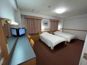 a hotel room with two beds and a flat screen tv at Hotel Alpha-One Niihama in Niihama