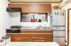 eine Küche mit Holzschränken und einem weißen Kühlschrank in der Unterkunft Takeuchi Goya in Chiba