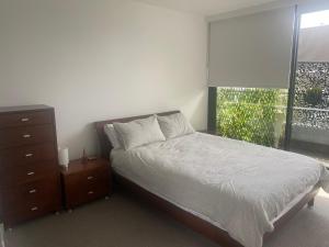 een slaapkamer met een bed, een dressoir en een raam bij Spacious 2 bed apartment, great location in Melbourne