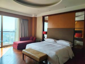 a bedroom with a large bed and a chair at Sheraton Zhoushan Hotel in Zhoushan