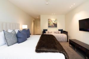 um quarto com uma grande cama branca e uma televisão de ecrã plano em Lordens Apartment 1 em Queenstown