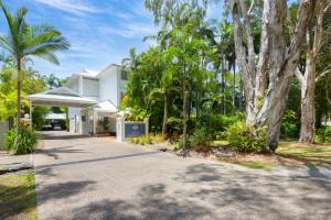 a driveway leading to a white building with trees at Coral Apartments Port Douglas in Port Douglas