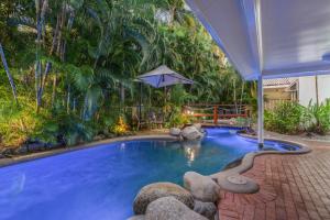 a swimming pool in a backyard with trees at Coral Apartments Port Douglas in Port Douglas