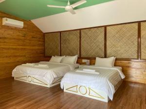 two beds in a room with wooden walls at Nov Koh Kong Resort in Phumĭ Srê Thmei