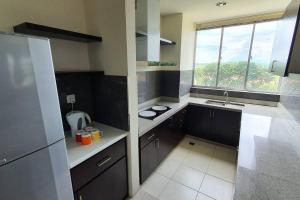 a kitchen with black cabinets and a sink and a window at Sky Residence -3 Bedrooms Condo at Cinta Sayang, Sungai Petani in Sungai Petani