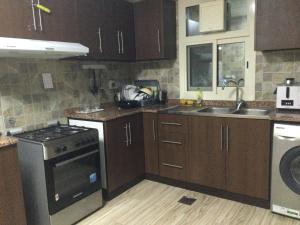 uma cozinha com armários de madeira e um forno com placa de fogão em 1 bedroom apartment em Fujairah