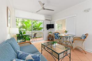 a living room with a blue couch and a table at Coral Apartments Port Douglas in Port Douglas