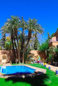 a swimming pool with palm trees in a yard at 16 Riads in Marrakesh