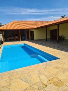 a blue swimming pool in front of a house at Recanto Girassol em São Roque - Rota do Vinho in São Roque