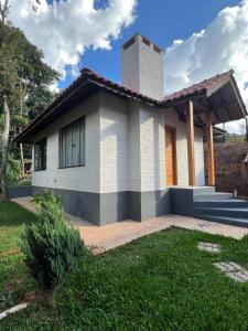 a house with a grass yard in front of it at Chales Bela Serra in Monte Verde