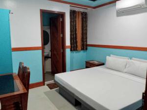 1 dormitorio con cama blanca y pared azul en SG Hotel, en El Nido