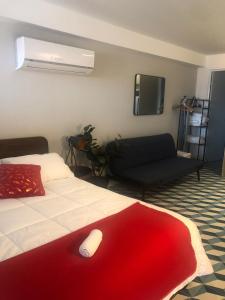 ein Schlafzimmer mit einem Bett mit einer roten Decke und einem Sofa in der Unterkunft Apartamento Casco Antiguo in Panama-Stadt