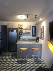 eine Küche mit zwei Hockern und einer Theke mit einem Kühlschrank in der Unterkunft Apartamento Casco Antiguo in Panama-Stadt