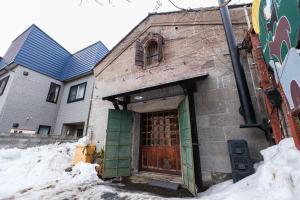 a brick building with a door in the snow at Stone Lodge 小樽 in Kita-hamachō