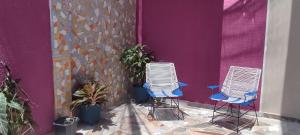 twee stoelen voor een paarse muur met planten bij Casa Katiuska in Mompos