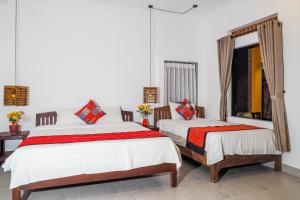 a bedroom with two beds and a mirror at Blue Beach Village Homestay in Hoi An